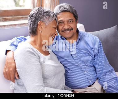 Genießen Sie jeden Moment zusammen. Ein liebevolles reifes Paar sitzt auf ihrem Sofa. Stockfoto