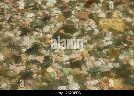 Ein Fragment eines Gebirgsflusses. Bunte Steine unter dem Wasser. Stockfoto