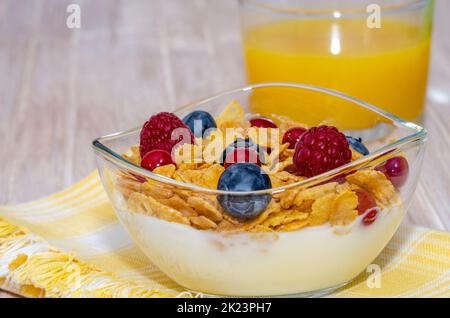 Schüssel Joghurt mit Müsli und Beeren mit Orangensaft zum Frühstück Stockfoto