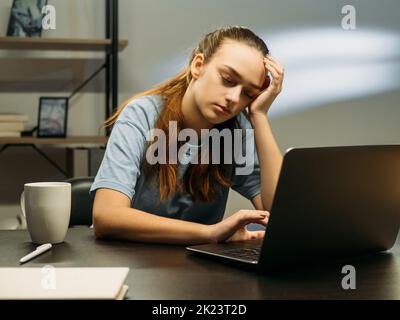 Burnout für die Arbeit. Ungesunde Arbeitslast. Freiberufler ermüdender Lebensstil. Abgenutzte Mitarbeiter schlafen auf dem Schreibtisch vor dem Laptop in dunklem Büroarbeitsplatz Stockfoto