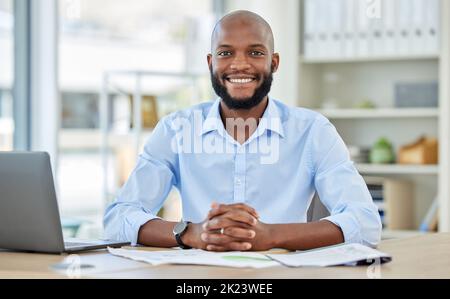 Porträt eines glücklichen afrikanischen Geschäftsmannes, der in seinem modernen Büro an seinem Schreibtisch sitzt. Professioneller schwarzer Manager, der ein Unternehmen arbeitet oder plant Stockfoto