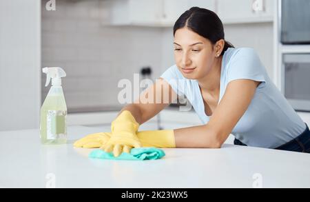 Putzfrau putzt Küchentheke mit Tuch, Sprühflasche und Gummihandschuhen im modernen Zuhause. Servicemitarbeiter, der mit Seifenflüssigkeit arbeitet Stockfoto