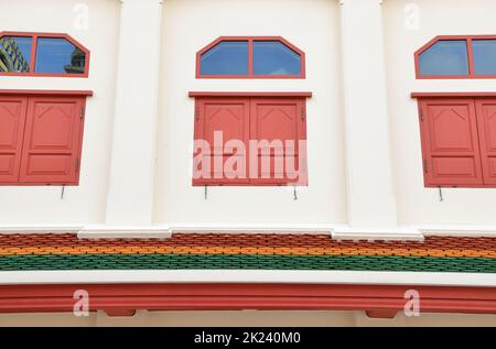 Staubige weiße, antike Gebäudefassade mit einem kleinen, wunderschönen roten Fenster. Stockfoto