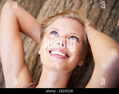 Die Natur macht sie glücklich. Eine junge Frau, die auf dem Waldboden liegt. Stockfoto