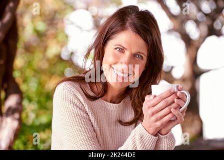 Zeit für eine Teepause. Ein Porträt einer schönen Frau, die in ihrem Garten Kaffee getrunken hat. Stockfoto