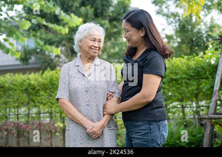 Asiatische ältere Frau mit Pflegekraft Tochter Wandern und Umarmung mit glücklich im Naturpark. Stockfoto