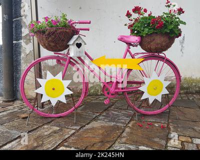 Ein schönes dekoratives altes Fahrrad mit Blumen in Töpfen Stockfoto