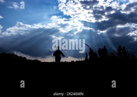 Sonnenstrahlen beleuchten Menschen. Einwanderung von Menschen. Blauer Himmel mit dunklen Wolken Stockfoto