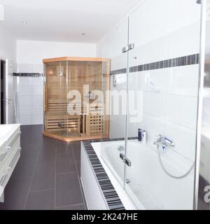 Badezimmer zu Hause mit hausgemachter Sauna Badewanne grau und weiß Fliesen, Sämaschine im Vordergrund Stockfoto