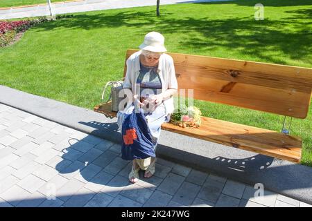 Weibliche Hände halten leere Handtasche nach dem Einkaufen im Park. Ältere Frau zeigt ihre leere Brieftasche. Insolvenz. Das Konzept der Armut. Stockfoto