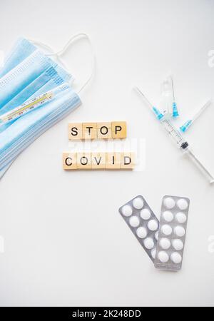 Stoppen Sie die Inschrift des Coronavirus. Vorbereitung für die Impfung gegen covid-19. Spritze, Impfstoff, Pillen, medizinische Maske Stockfoto