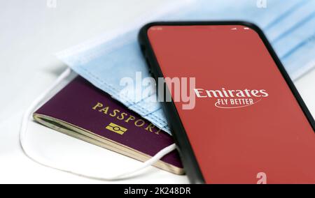 Dubai, VAE, Juli 2021: Rufen Sie mit der Emirates Airlines App auf dem Bildschirm an, der über einer Schutzmaske und einem Reisepass liegt. Reisesicherheit während Coronaviru Stockfoto