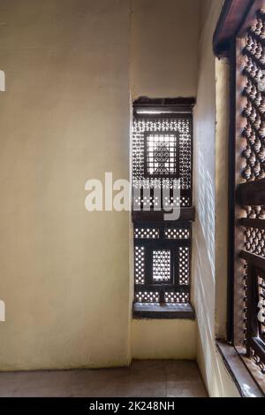 Ecke von zwei verzackten Grange Holz verzierten Fenstern - Maschrabiya - in Steinmauer in verlassenen Gebäude Stockfoto