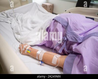 Nahaufnahme der Kochsalzlösung von Patientinnen in rosa Kleidern, die auf dem Krankenhausbett liegen Stockfoto