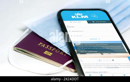 Amsterdam, NED, Juli 2021: Telefonieren Sie mit der KLM Airlines App auf dem Bildschirm, der über einer Schutzmaske und einem Reisepass liegt. Reisesicherheit und Einschränkungen d Stockfoto
