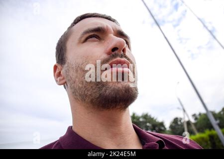 Bart auf dem Gesicht eines jungen Mannes. Bärtiger junger Mann, in der Nähe von Stoppeln. Mehr als eine Woche nicht rasiert. Haare auf dem Gesicht eines Mannes, ein kurzer Bart. Stockfoto