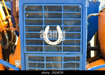 Hufeisen auf der Motorhaube des Traktors. Das Bild war auf einem Parkplatz der Traktoren in einem ländlichen Garage am Ortsrand von Temryuk genommen. Stockfoto