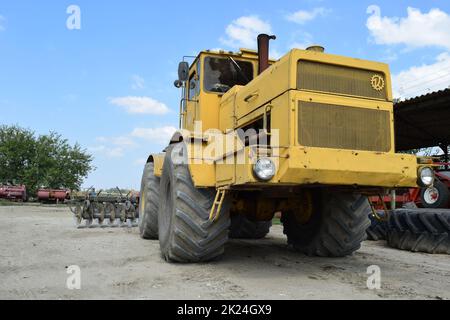 Russland, Temryuk - 15. Juli 2015: Großer gelber Traktor. Alte sowjetische Landmaschinen Stockfoto