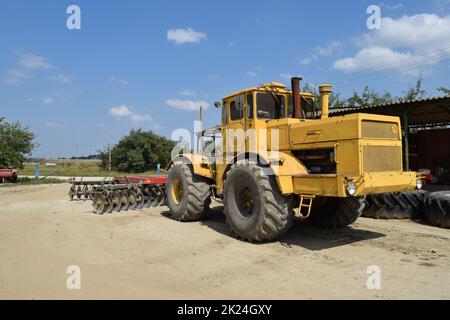 Russland, Temryuk - 15. Juli 2015: Großer gelber Traktor. Alte sowjetische Landmaschinen Stockfoto