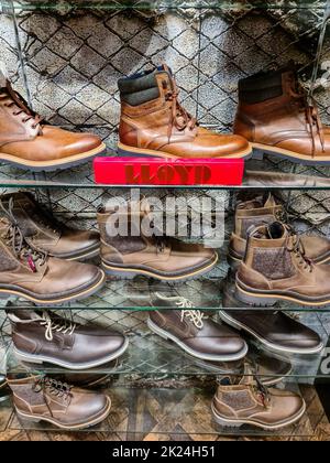 Zahlreiche braune und schwarze Lederstiefel der Marke Lloyd auf einem Regal in einem Schuhgeschäft Stockfoto
