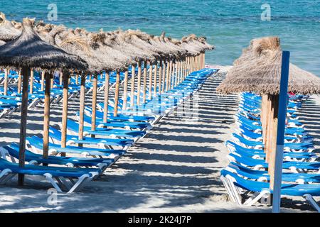 Liegestühle in einer Reihe und Sonnenschirme am Strand im Sommer. Stockfoto