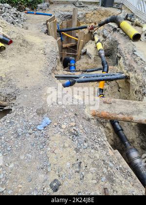 Arbeiten an der Installation von Engineering- und Heizsystemen. Zwei Kunststoffrohre, eine gelbe für Gasleitung und eine schwarze für Stromleitungen. Sie befinden sich in einer SA Stockfoto