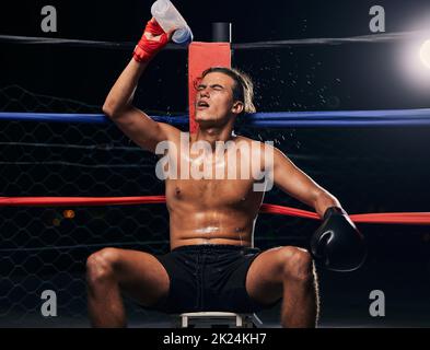 Boxsportler mit Wasserflasche, müde nach dem Training, Training oder Training im Ring. Professionelle Boxer Ruhe und Hydrat nach dem Fitness mma, muay Stockfoto