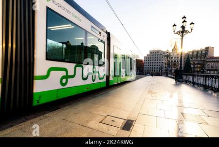 BILBAO, SPANIEN-DECEMBER 19, 2021 : Bürgersteig mit Menschen zu Fuß in der Nähe von Euskotren Stadt Straßenbahn fährt auf Straßenbahnlinie. Moderner Verkehr in Europa. Gehweg hinein Stockfoto