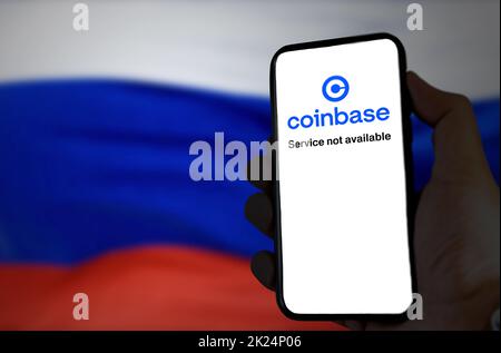 Moskau, RUS, 2022. März: Hand hält ein Telefon, während die Coinbase-App außer Betrieb ist und die russische Flagge im Hintergrund verschwommen ist. Im März Stockfoto