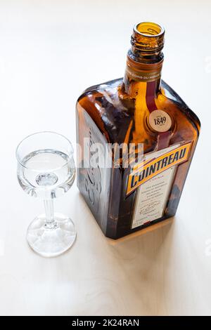 Moskau, Russland - 20. März 2022: Likörglas und Flasche französischer Cointreau-Likör auf hellem Tisch. Cointreau ist ein dreifacher sec-Likör mit Orangengeschmack Stockfoto