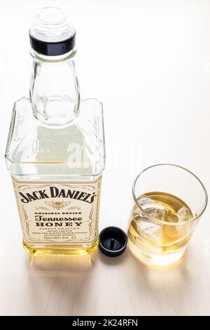 Moskau, Russland - 26. März 2022: Glas und offene Flasche von Jack Daniel's Tennessee Honey Likör auf hellem Tisch. Es ist Honiglikör mit weniger t gemischt Stockfoto