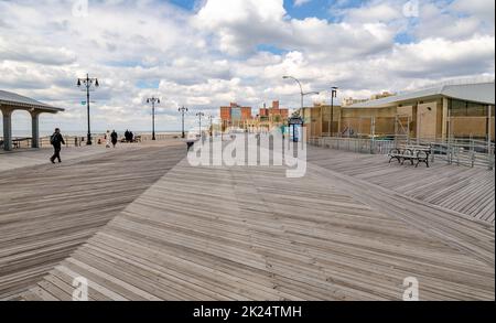 Strandpromenade auf Coney Island, Brooklyn mit Menschen, die herumlaufen, Wohngebäude im Hintergrund, Brooklyn New York City im Winter da Stockfoto