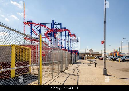 Soarin' Eagle Rollercoaster rot und blau im Luna Park Amusement Park, Coney Island, Brooklyn, Blick von der Seite mit der Stadtstraße und geparkt c Stockfoto