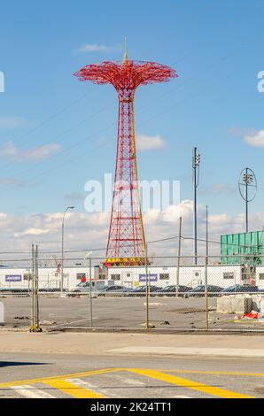 Red Parachute Jump im Luna Park Amusement Park, Coney Island, Brooklyn während des Wintertages, Blick aus der Ferne, mit Stadtstraße und Zaun davor, Stockfoto