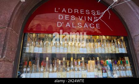 Colmar, Frankreich - 30. Dezember 2021: Mehrere Flaschen erlesener Weine, die auf Holzregalen in der Nähe von Kisten in einem lokalen Geschäft gelagert werden. Elsässische Weinstraße. Reisen und nach Stockfoto