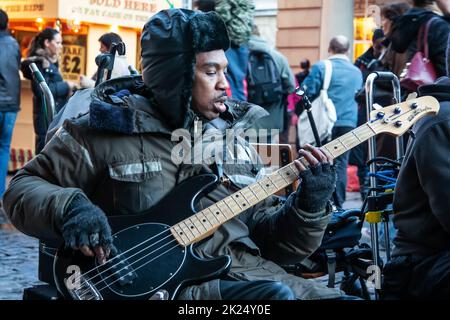 London, Großbritannien, 25. November 2006: Unbekannter Straßenmusikant spielt Bass Gitarre und Schilder am Covent Garden. Straßenkünstler sind oft in t Stockfoto