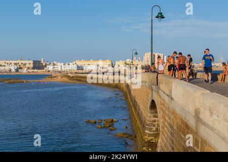 Cisz, Spanien - 16. August 2021. Die Menschen genießen La Caleta mit dem Schloss San Sebastian, einer Festung auf der Insel La Caleta, im Hintergrund. Blick von Stockfoto