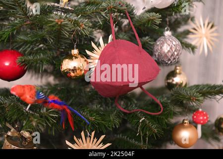 FFP2-Maske hängt auf einem Weihnachtsbaum, Österreich, Europa - FFP2 Maske hängt an einem Weihnachtsbaum, Österreich, Europa Stockfoto