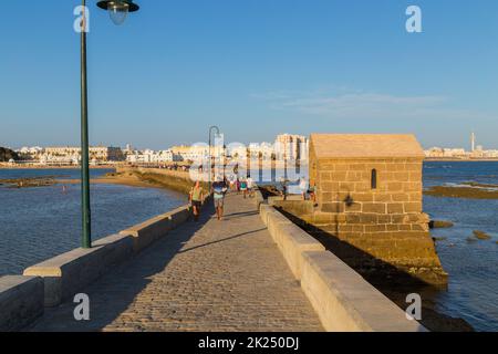 Cisz, Spanien - 16. August 2021. Die Menschen genießen La Caleta mit dem Schloss San Sebastian, einer Festung auf der Insel La Caleta, im Hintergrund. Blick von Stockfoto