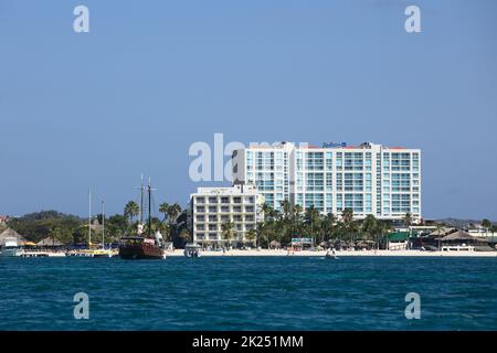 PALM BEACH, ARUBA - 17. OKTOBER 2021: Blick vom Meer auf das Hotel Radisson Blu, in den vorderen Gebäuden des Holiday Inn Resort und Ausflugsboote entlang P Stockfoto