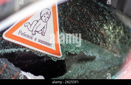 Warnschild an einem Autofenster. Übersetzung: Kind im Auto. Krieg Russlands gegen die Ukraine. Ein Auto von Zivilisten, die während des russischen Militärs angeschossen wurden Stockfoto