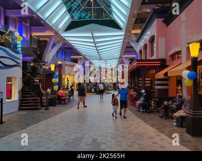 Miami, USA - 29. April 2022: Die Passagiere gehen auf Promenade auf dem Kreuzfahrtschiff Symphony of the Seas von Royal Caribbean . Das Innenrauminterier des Schiffs Stockfoto