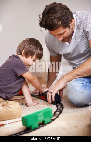 Spaß mit Papa auf der Eisenbahn. Ein Vater und Sohn spielen mit einem Spielzeugzug. Stockfoto