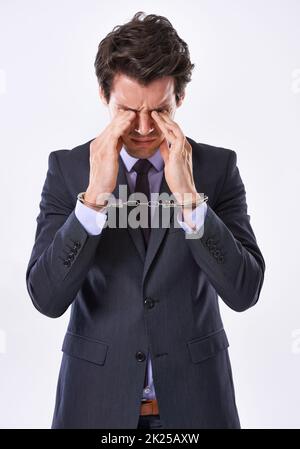 Durch Stress gekettet. Studioaufnahme eines hübschen jungen Geschäftsmannes in Handschellen. Stockfoto