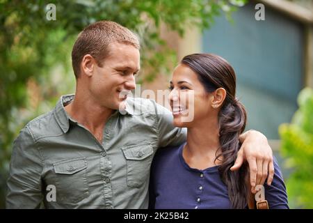 Verloren im Dunst der Romantik im Frühling. Beschnittene Ansicht eines glücklichen jungen Paares, das zusammen im Park steht. Stockfoto