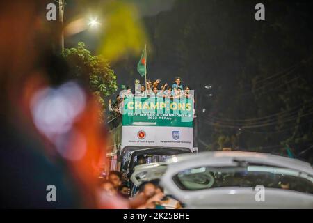 Die Fußballnationalmannschaft der Frauen feiert auf dem Weg zum Bangladesh Football Federation House. Die bangladeschische Fußballnationalmannschaft der Frauen hält die Trophäe der SAFF-Frauenmeisterschaft in einem offenen Bus auf dem Weg vom internationalen Flughafen Hazrat Shahjalal zum BFF-Haus ab, während Tausende von einfachen Menschen die Spieler am Straßenrand begrüßen. Stockfoto