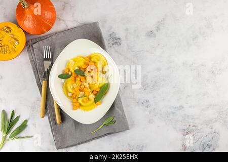 Saisonales Herbstrezept. Kürbisravioli mit Salbei, Parmesan und Olivenöl. Stockfoto