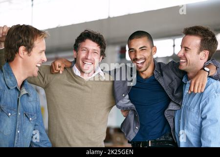 Feiern eines weiteren Teamsieges. Eine Gruppe männlicher Mitarbeiter jubelt in einem modernen Büro zusammen. Stockfoto