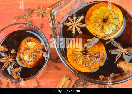 Heißes Wintergetränk zu Weihnachten oder Neujahr, würziger Grog-Cocktail, Sangria oder Glühwein mit Tee, Zitrone, Rum, Zimt, Anisstern. Weihnachtlicher Glühwein in einem Glas auf einem Holztisch. Nahaufnahme. POV - direkt darüber Stockfoto