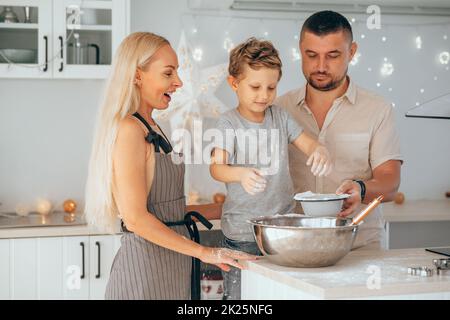 Glückliche Familie Mutter, Vater und Sohn backen Weihnachtskekse in der gemütlichen Küche. Stockfoto